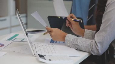 Genç bir kadın ofis masasında oturuyor ve dizüstü bilgisayar kullanıyor.