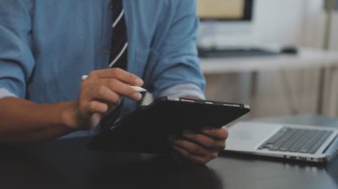 Ofiste dijital tablet ve tabletle çalışan bir adam var.