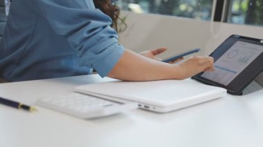 Tablet bilgisayar ve finansal tabloyla çalışan iş kadını ofiste..