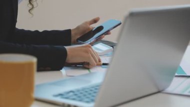 Modern bir ofiste dizüstü bilgisayar kullanan genç bir kadın.