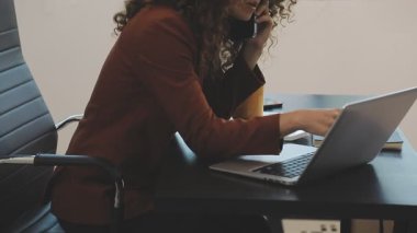 Ofiste dizüstü bilgisayarla çalışan genç bir kadın.