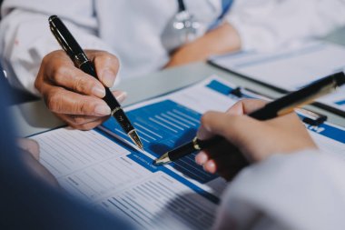 Erkek ve kadın doktorlar bir hastane odasında toplantı yapıyorlar..