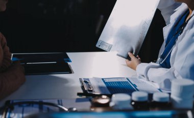 Doktor, emekliye ayrılmış yaşlı kadına akciğer röntgeni çeken hastanın sağlık ve hayat sigortası planlarını kullanarak hastane bakım evindeki hastalara tedavi yöntemlerini anlattı.