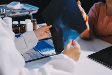 Doktor, emekliye ayrılmış yaşlı kadına akciğer röntgeni çeken hastanın sağlık ve hayat sigortası planlarını kullanarak hastane bakım evindeki hastalara tedavi yöntemlerini anlattı.