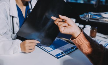 Doktor, emekliye ayrılmış yaşlı kadına akciğer röntgeni çeken hastanın sağlık ve hayat sigortası planlarını kullanarak hastane bakım evindeki hastalara tedavi yöntemlerini anlattı.