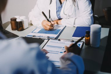 Erkek ve kadın doktorlar bir hastane odasında toplantı yapıyorlar..