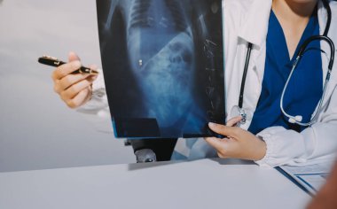 Doktor, emekliye ayrılmış yaşlı kadına akciğer röntgeni çeken hastanın sağlık ve hayat sigortası planlarını kullanarak hastane bakım evindeki hastalara tedavi yöntemlerini anlattı.