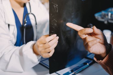 Doktor, emekliye ayrılmış yaşlı kadına akciğer röntgeni çeken hastanın sağlık ve hayat sigortası planlarını kullanarak hastane bakım evindeki hastalara tedavi yöntemlerini anlattı.