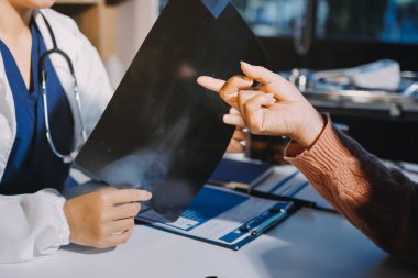 Doktor, emekliye ayrılmış yaşlı kadına akciğer röntgeni çeken hastanın sağlık ve hayat sigortası planlarını kullanarak hastane bakım evindeki hastalara tedavi yöntemlerini anlattı.