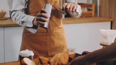 Genç barista tezgahta fincana kahve dolduruyor.