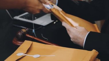 Takım elbiseli bir işadamı ofisinde belge ve kalem tutuyor.