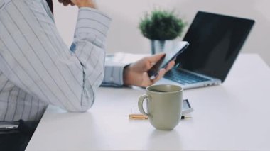 İşadamı elinde laptopla ofiste kahve tutuyor.