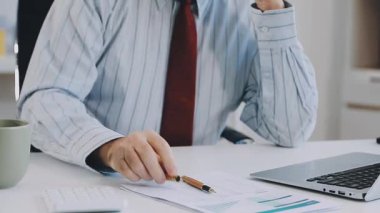 Masada dizüstü bilgisayar ve hesap makinesiyle çalışan bir iş adamı.