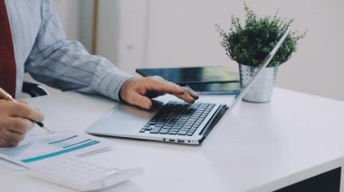 İş adamı masanın üstünde dizüstü bilgisayar ve hesap makinesi kullanıyor..