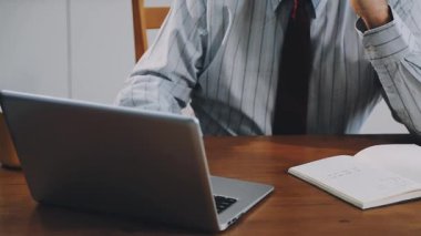 Genç işadamı iş yerinde dizüstü bilgisayar ve akıllı telefon kullanıyor.