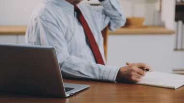 Genç işadamı ofiste dizüstü bilgisayarla çalışıyor. İş adamı akıllı telefonunu kullanıyor..