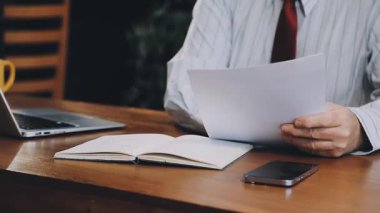 İşadamı dizüstü bilgisayar kullanıyor ve tahta bir masaya yazı yazıyor.