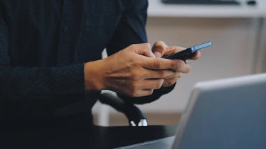 Ofiste akıllı telefonla çalışan bir adam.