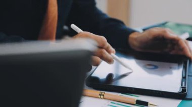 Ofisteki masada tablet bilgisayar ve kalem kullanan bir iş adamı