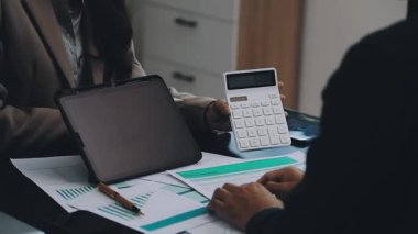 İş kadını ofiste dizüstü bilgisayar ve hesap makinesi kullanıyor.