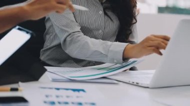 Genç iş kadını masada oturuyor ve bilgisayarla çalışıyor.