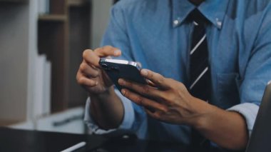 Modern bir ofiste akıllı telefon kullanan bir iş adamı..