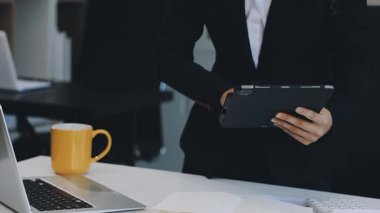 Ofis masasında dizüstü bilgisayar ve akıllı telefonla çalışan genç bir işadamı.