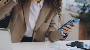 Akıllı telefon kullanan ve ofiste kahve içen bir kadın. iş kavramı