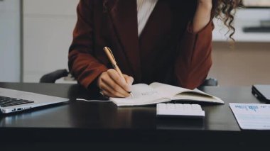 İş kadını ofiste deftere yazı yazıyor.