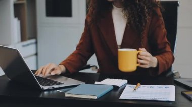 Dizüstü bilgisayarda çalışan ve evinde kahve içen bir kadın.