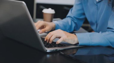 Genç iş kadını dizüstü bilgisayarda yazıyor.