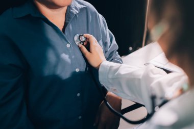 Konuşurken kalp atışı ve semptomlarını incelemek için steteskop kullanan erkek doktorun el görüntüsü.