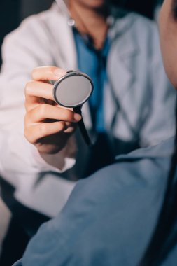 Konuşurken kalp atışı ve semptomlarını incelemek için steteskop kullanan erkek doktorun el görüntüsü.