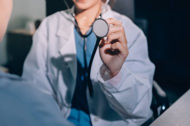 Konuşurken kalp atışı ve semptomlarını incelemek için steteskop kullanan erkek doktorun el görüntüsü.