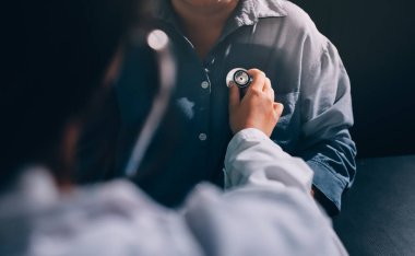 Konuşurken kalp atışı ve semptomlarını incelemek için steteskop kullanan erkek doktorun el görüntüsü.