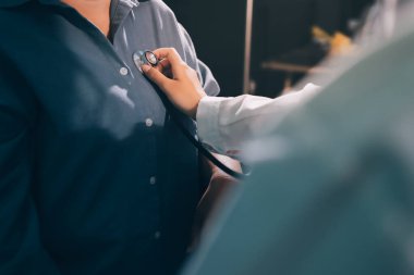 Konuşurken kalp atışı ve semptomlarını incelemek için steteskop kullanan erkek doktorun el görüntüsü.