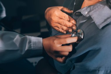 Konuşurken kalp atışı ve semptomlarını incelemek için steteskop kullanan erkek doktorun el görüntüsü.