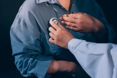 Konuşurken kalp atışı ve semptomlarını incelemek için steteskop kullanan erkek doktorun el görüntüsü.