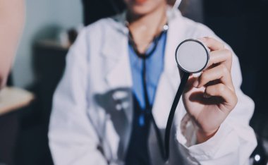 Konuşurken kalp atışı ve semptomlarını incelemek için steteskop kullanan erkek doktorun el görüntüsü.