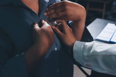 Konuşurken kalp atışı ve semptomlarını incelemek için steteskop kullanan erkek doktorun el görüntüsü.