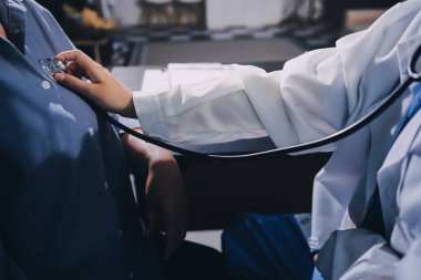 Konuşurken kalp atışı ve semptomlarını incelemek için steteskop kullanan erkek doktorun el görüntüsü.