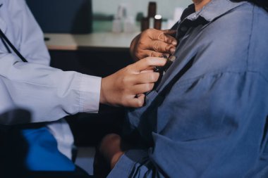 Konuşurken kalp atışı ve semptomlarını incelemek için steteskop kullanan erkek doktorun el görüntüsü.