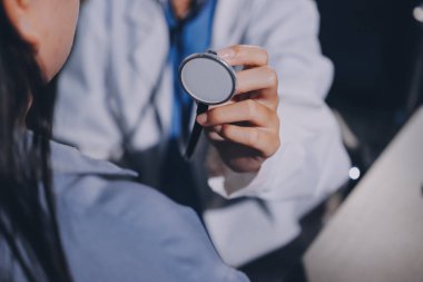 Konuşurken kalp atışı ve semptomlarını incelemek için steteskop kullanan erkek doktorun el görüntüsü.