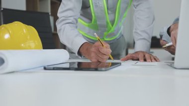 Mühendis ofiste planlar üzerinde çalışıyor.