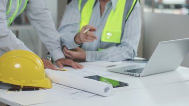 Sarı tişörtlü, laptoplu, beyaz kasklı ve yeşil klasörlü genç bir mimar..