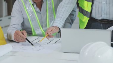 İnşaat alanında sarı miğferi ve planı olan mühendis mimar.
