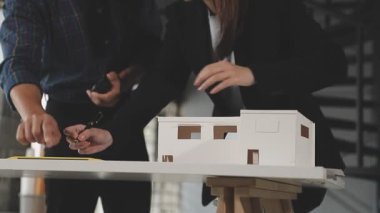 Ofiste genç bir çift mimar ve emlakçı var. Yeni bir ev modeli tutuyorlar..