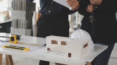 Mimar mühendisi, planlar ve inşaat konseptiyle birlikte ofiste plan üzerinde çalışıyor..