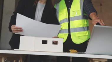 Mühendis ve mimar ekibi ofis binasının planlarıyla birlikte ofiste çalışıyor..