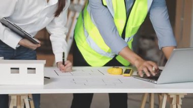 Mimar ve mimar mühendisi bilgisayar ve ofis içinde mimari planla çalışıyor. Gayrimenkul ve inşaat kavramı